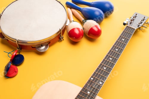 Preview: Wooden colorful and blue maracas, tambourine, castanets and acoustic guitar on yellow background