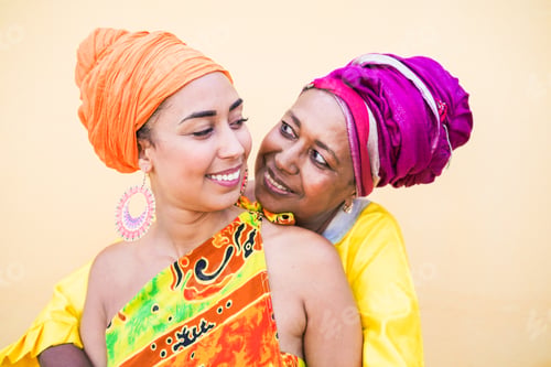Preview: Beautiful african mother and daughter hug each other while wearing traditional dress and smile