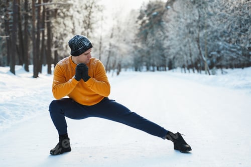 Preview: Athletic man doing warming up before his winter workout in snowy park