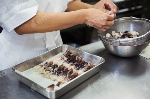 Preview: High angle close up of chef working in the kitchen of a Japanese sushi restaurant, placing Torigai,