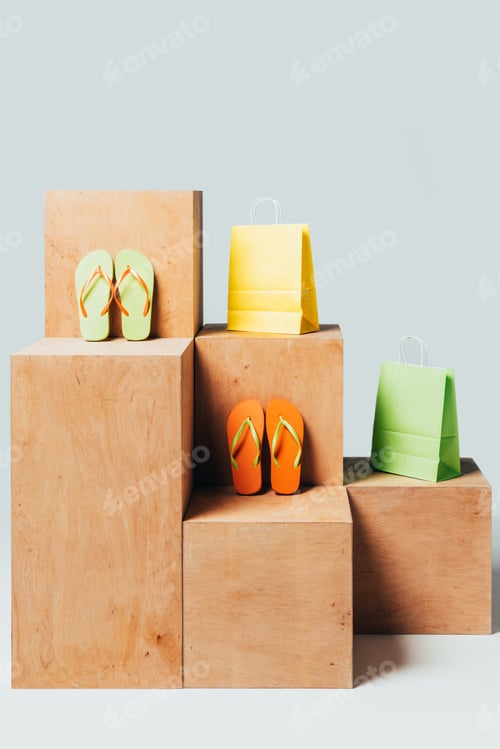 Preview: colored paper bags and flip flops on wooden stands, summer sale concept