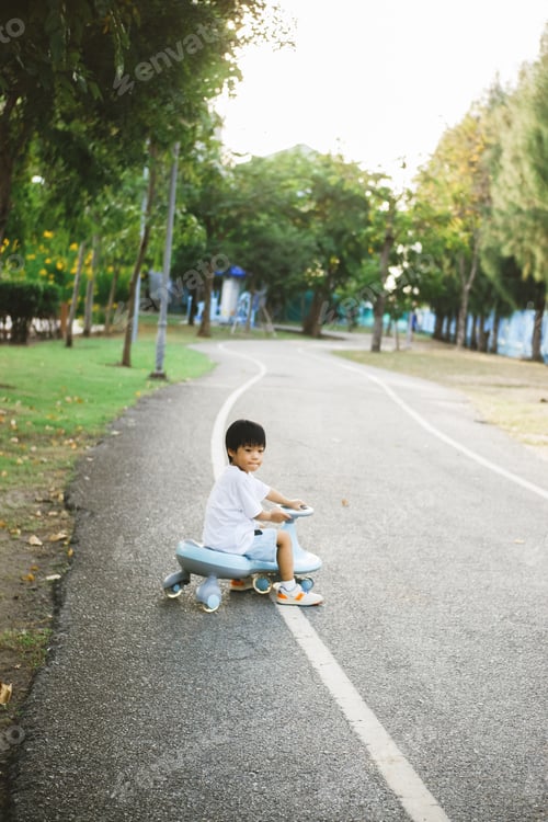 Preview: Little Asian boy riding bicycle toy in the park with happy face