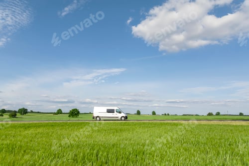Preview: White Van Driving Through Green Field on Sunny Day