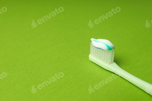 Preview: Toothbrush with toothpaste on green background, space for text
