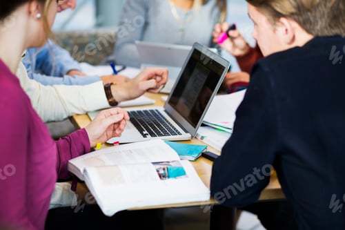 Preview: Group of students engaged in study session at a busy table with laptop and notes.
