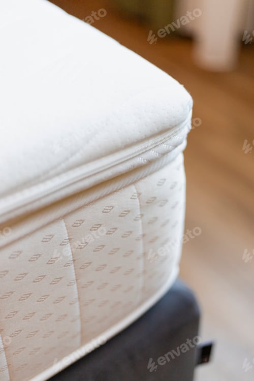 Preview: A close-up view of a soft, plush mattress topper resting atop a mattress in a modern bedroom