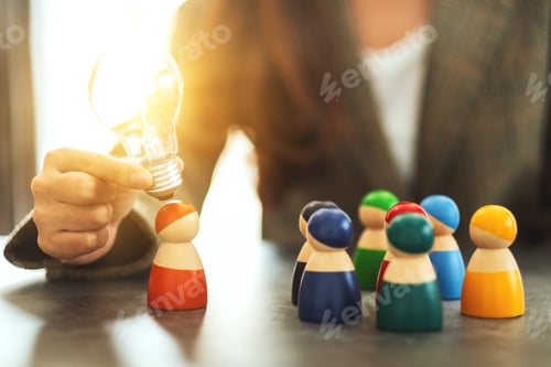 Preview: a woman holding and putting a light bulb over one of a different colors wooden people toy