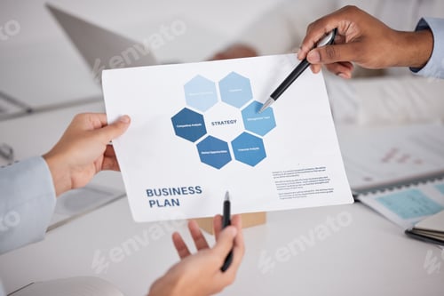 Preview: High angle shot of a group of unrecognizable businesspeople looking over paperwork in the boardroom