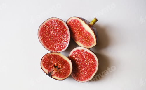 Preview: Closeup of cut figs on a white surface under the lights