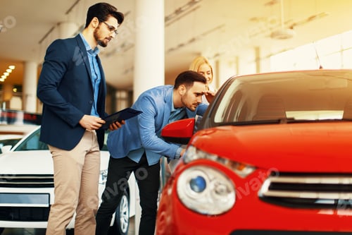 Preview: Young couple choosing new car for buying in dealership shop