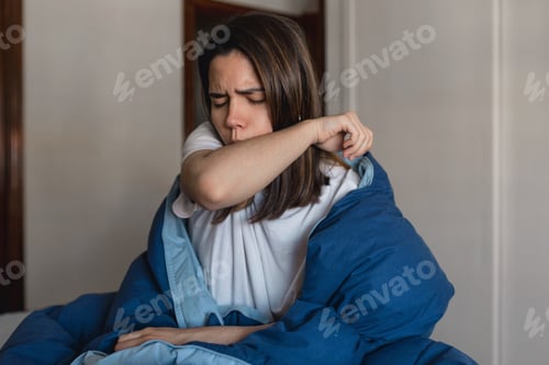 Preview: Young ill woman coughing into her upper sleeve