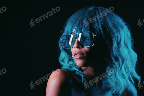 Preview: Portrait of alluring blue haired mixed race girl in neon light. Fashion, glamour, model concept.