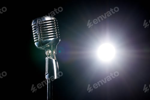 Preview: Vintage vocal microphone in the dark on a concert stage with spot lighting.