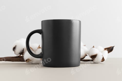 Preview: Black mug mockup with a cotton branch on the beige table.