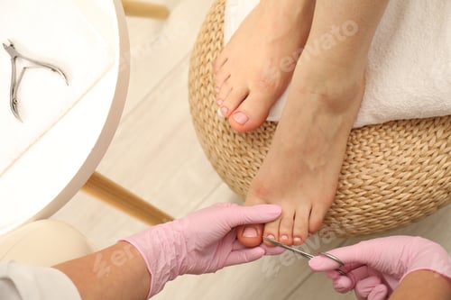 Preview: Professional pedicurist cutting client`s toenails with scissors in beauty salon, closeup