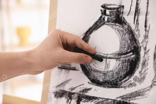 Preview: Young man painting vase with black wax crayon in artist's studio, closeup