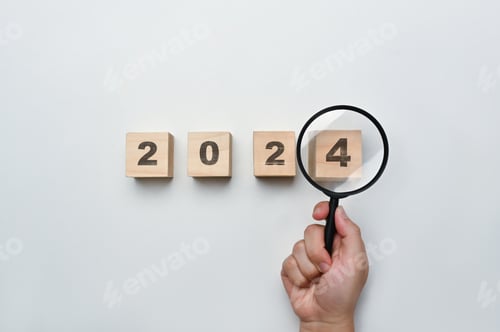 Preview: Magnifying glass and wooden cubes with 2024 year number on white background.