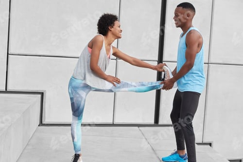 Preview: Horizontal view of fit female stretches legs, warms up before race competitons, boyfriend helps her,
