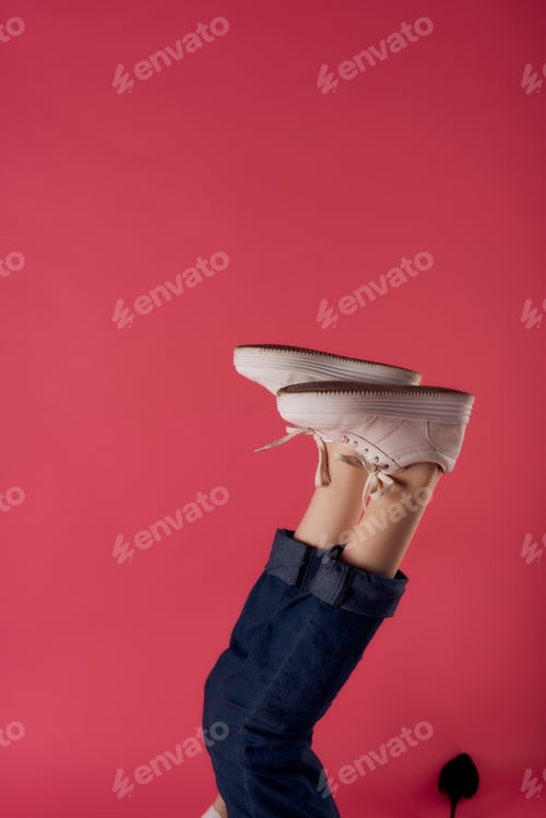 Preview: inverted female legs in white sneakers fashion studio pink background