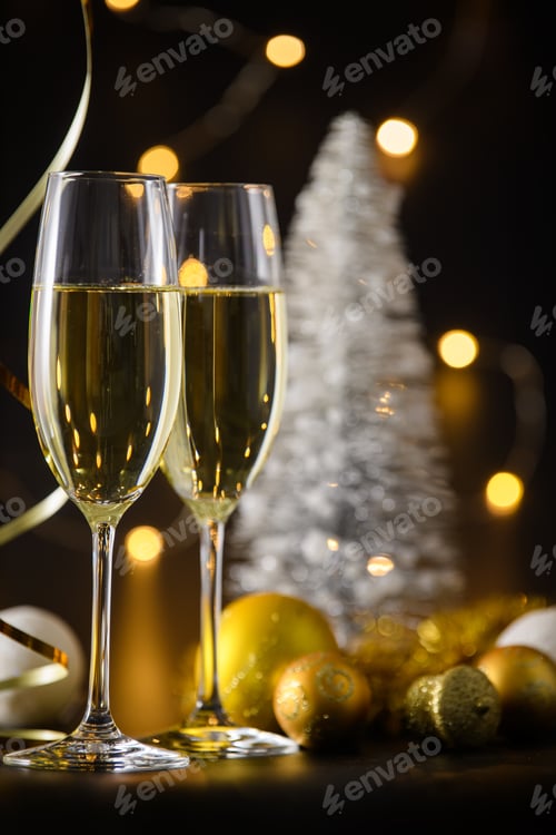 Preview: Two glasses of champagne or wine with bokeh background with christmas ball and tree