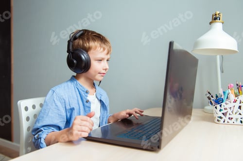 Preview: Portrait of little boy in headset laptop, studying online at home, interested happy student typing