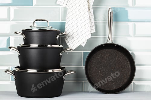 Preview: New black cookware against blue tile wall