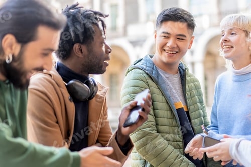 Preview: Diverse group of young adults socializing with smartphones outdoors in urban setting