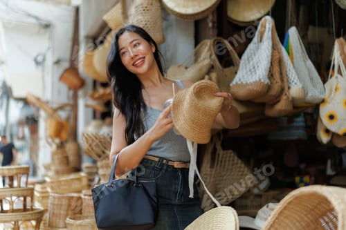 Preview: Tourist holding a straw hat and a drink at a traditional market