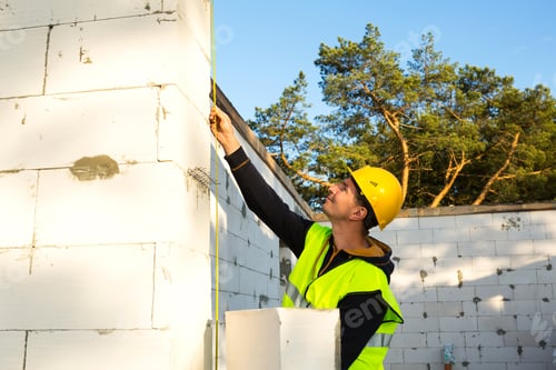 Preview: Construction worker at construction site measures the length of the window opening