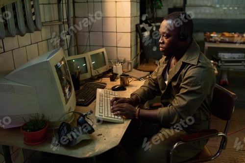 Preview: Black Man Hacking Code On Computer In Abandoned Building