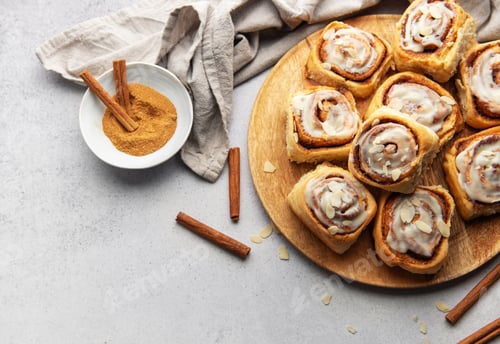 Preview: Freshly baked cinnamon rolls with icing and almond flakes on wooden tray