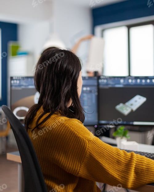 Preview: Young woman industrial engineer working at pc with two monitors