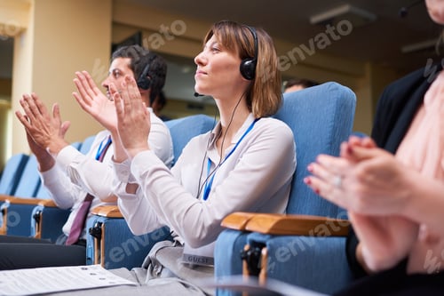 Preview: Happy young businesswoman and her foreign colleagues in headpones