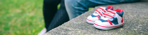 Preview: Closeup of small baby sneakers over bench