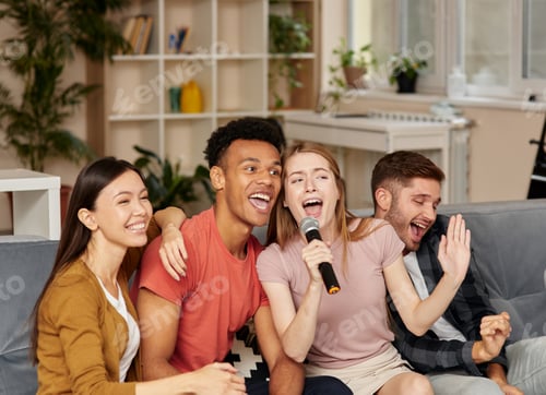 Preview: Hang out with friends. Cheerful young multicultural friends playing karaoke at home, singing with