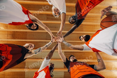 Preview: Low angle view of a multiracial basketball team and their coach joining hands