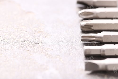 Preview: Different screwdriver bits on grey table, closeup. Space for text