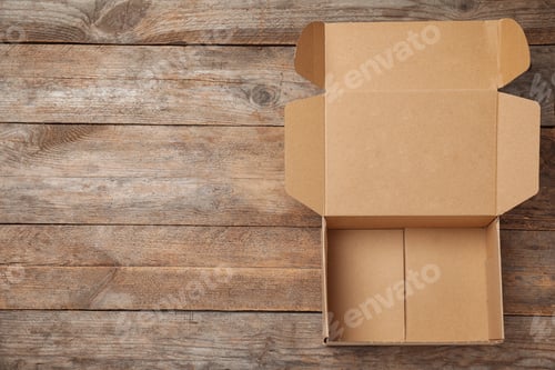 Preview: Open cardboard box on wooden background, top view. Space for text