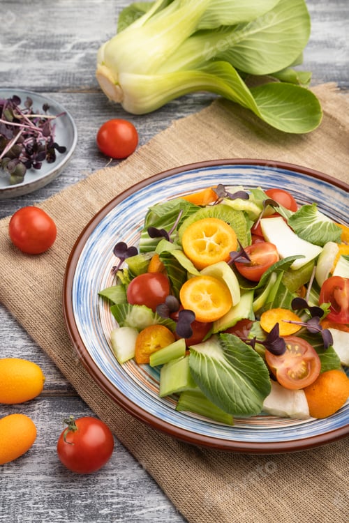 Preview: Vegetarian salad of pac choi cabbage, kiwi, tomatoes, kumquat, microgreen sprouts on gray