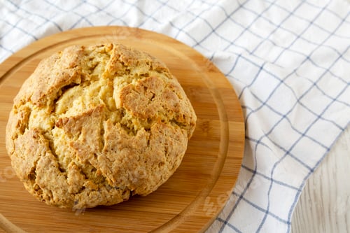 Preview: Homemade Irish Soda Bread on a round bamboo board, side view. Close-up.