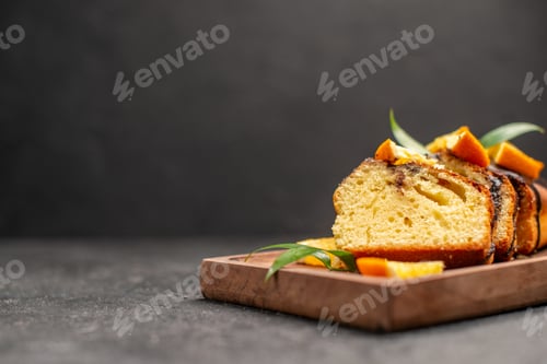 Preview: Close up view of freshly baked soft cake slices on wooden cutting board on dark table