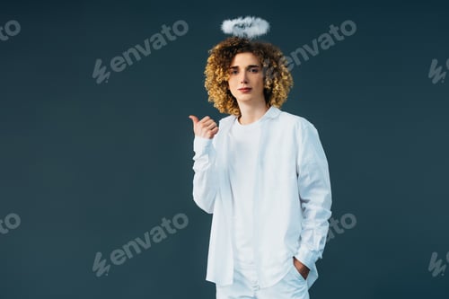 Preview: curly teenager in angel costume with halo above head showing thumb up isolated on green