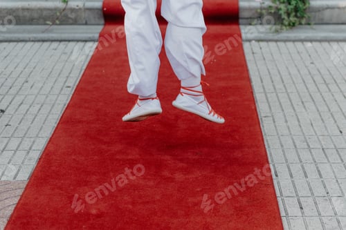 Preview: Person in white cloth and gym shoes jumping on red carpet