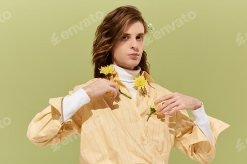 Preview: Handsome young man showcases feminine fashion style against a soft green backdrop