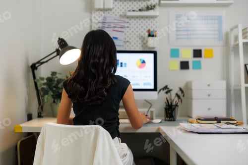 Preview: Businesswoman working from home office analyzing charts on computer screen