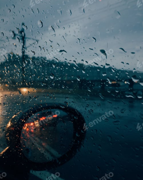 Preview: Raindrops outside car with auto mirror, unrecognizable driver drives car at bad weather.