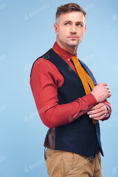 Preview: handsome stylish man in formal wear adjusting shirt isolated on blue