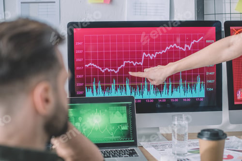 Preview: Selective focus of data analyst pointing at chart on computer monitor to colleague in office