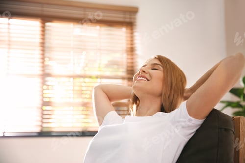 Preview: Young woman relaxing in armchair near window at home. Space for text