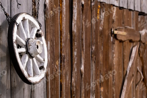 Preview: An old wooden carriage wheel hanging on the barn wall